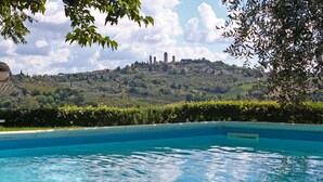 Une piscine avec vue sur une colline parsemée de bâtiments.