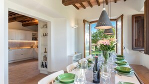 A dining area with a table set for a meal, a wine bottle, and a vase of flowers.