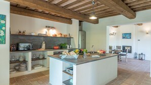 Uma cozinha moderna com uma ilha central, vigas de madeira e um espaço de jantar com lareira.
