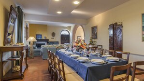 Ein Essbereich mit einem langen Tisch, gedeckt für eine Mahlzeit, mit Stühlen, einer Couch und einem Kamin.