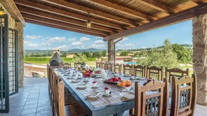 An outdoor dining area with a stone oven, wooden chairs, and a view of the countryside. - Podere Torricella 16 4 (Narni)
