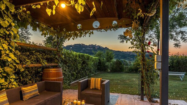 Un espace extérieur aménagé avec des meubles en osier et offrant une vue sur une colline.