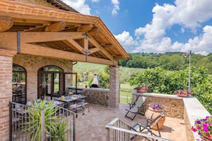 A patio with outdoor seating, stone walls, and a view of a lush landscape.