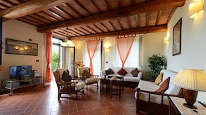 A cozy living room with a wooden ceiling, a television, and comfortable seating.