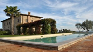 A stone building with a pool, surrounded by greenery and trees. - Villa Siena 10 in Castelnuovo Berardenga (Castelnuovo Berardenga)
