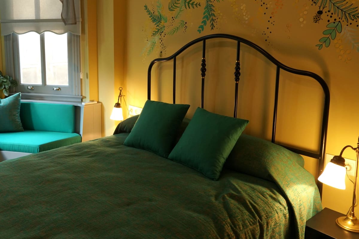 A bed with a headboard, a bedside table with a lamp, and a window with curtains.