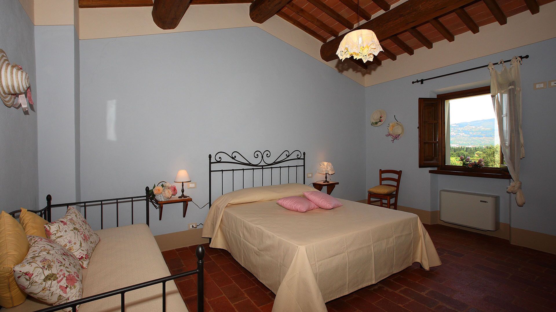 A bedroom with a bed, a chair, a window with a view, and a radiator.