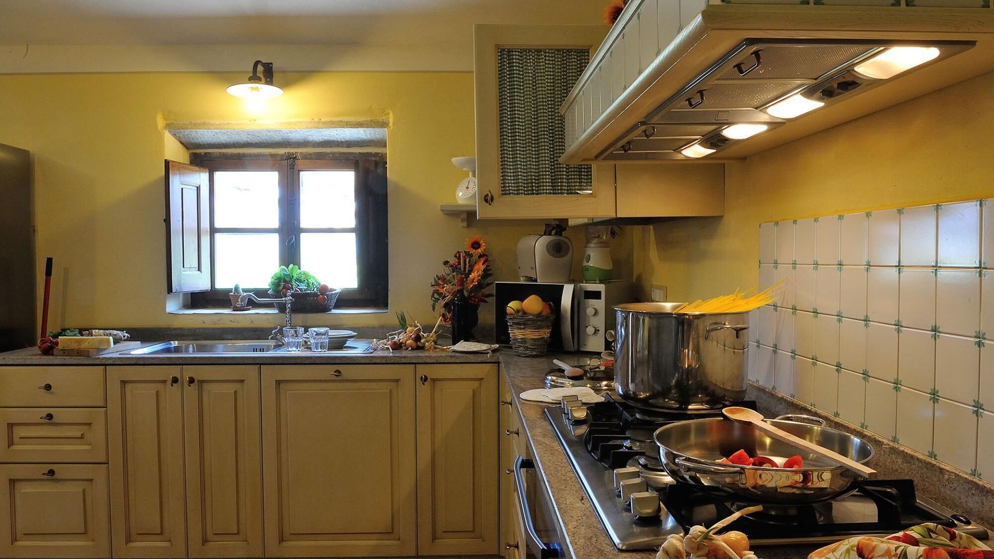 Una cucina con una finestra, un lavandino, un fornello e diversi utensili da cucina.