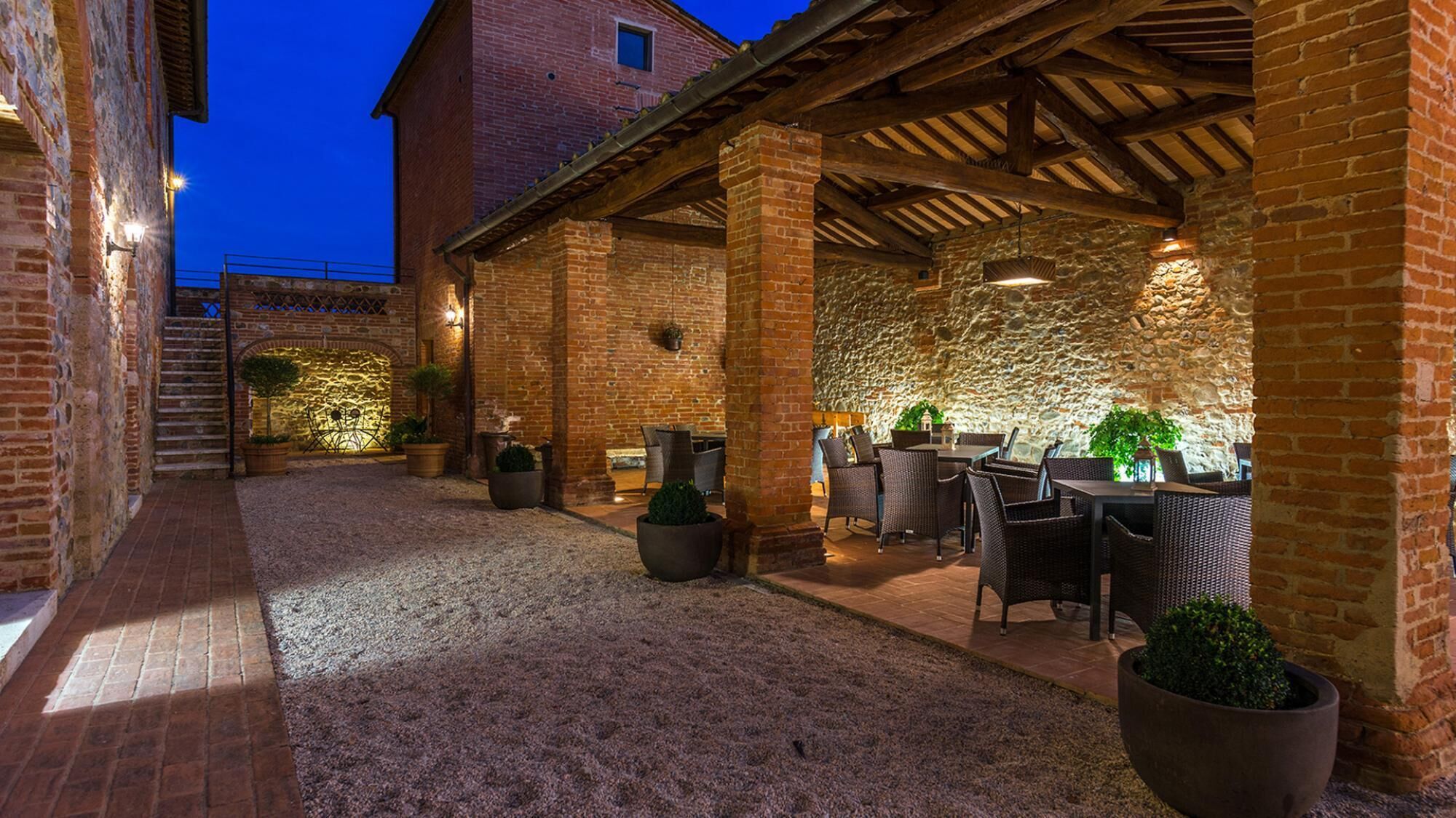 An outdoor patio area with brick walls, stone accents, and wicker furniture.