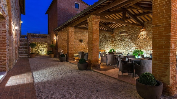 An outdoor patio area with brick walls, stone accents, and wicker furniture.
