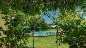 Un espace piscine offrant une vue dégagée sur le bassin, entouré d’une pelouse bien entretenue et d’arbres.
