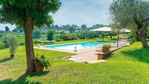 A rectangular swimming pool with a paved deck, surrounded by well-maintained grass and trees. - Villa Di Morice 12 in Castel Ritaldi (Castel Ritaldi)