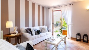 A living room with a white sofa, a glass coffee table, and striped walls. - Villa Elena 9 1 in Coli (Massarosa)