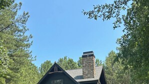 Una cabaña de madera con chimenea, un porche con asientos y una bandera.