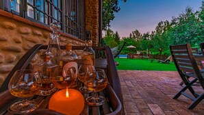 A patio area with a table set for a meal, featuring various bottles and glasses.