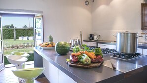 Een moderne keuken met een groot kookeiland, een gasfornuis en diverse keukengerei.