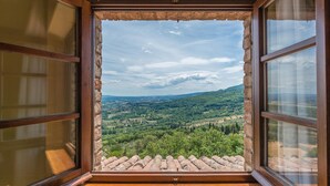 Une pièce rustique dotée d’une grande fenêtre donnant sur une vallée verdoyante.