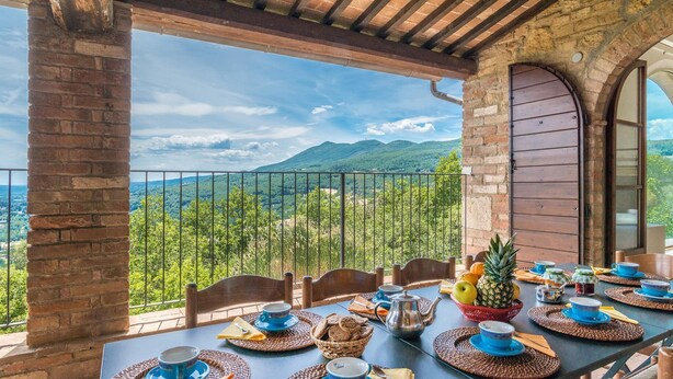 Une terrasse avec une table préparée pour le petit-déjeuner, offrant une vue sur un paysage montagneux.