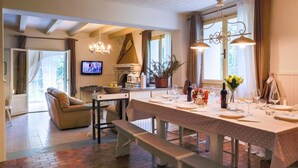 Un comedor acogedor con una mesa larga dispuesta para dos, un sofá cómodo y un televisor al fondo.