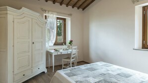 A bedroom with a bed, a desk, a chair, a wardrobe, and a window with curtains. - La Vecchia Fonte 15 (Volterra)
