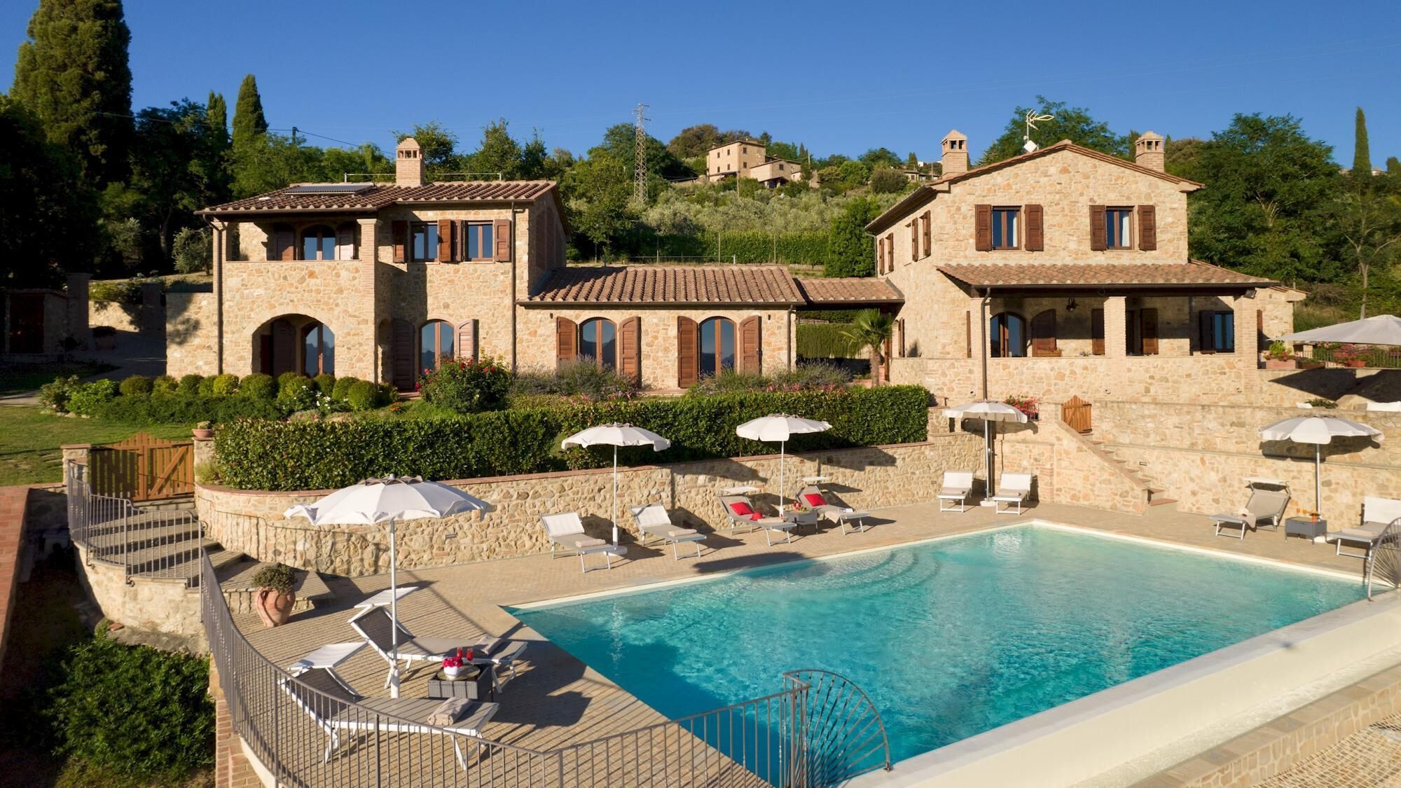 A stone villa with a swimming pool, outdoor seating, and a garden.