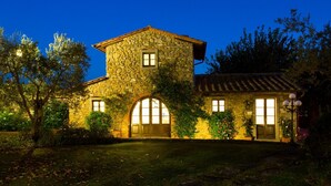 A stone building with arched windows and a tiled roof, surrounded by trees and a well-maintained lawn. - La Capannina 2 2 in Camucia (Cortona)