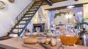 A cozy living room with a wooden staircase, a fireplace, a dining table with bread and tea, and a decorative wall with numbers. - La Capannina 2 2 in Camucia (Cortona)