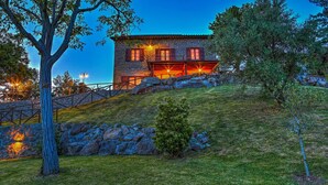 A stone house with a sloped roof, a stone wall, and a small garden.