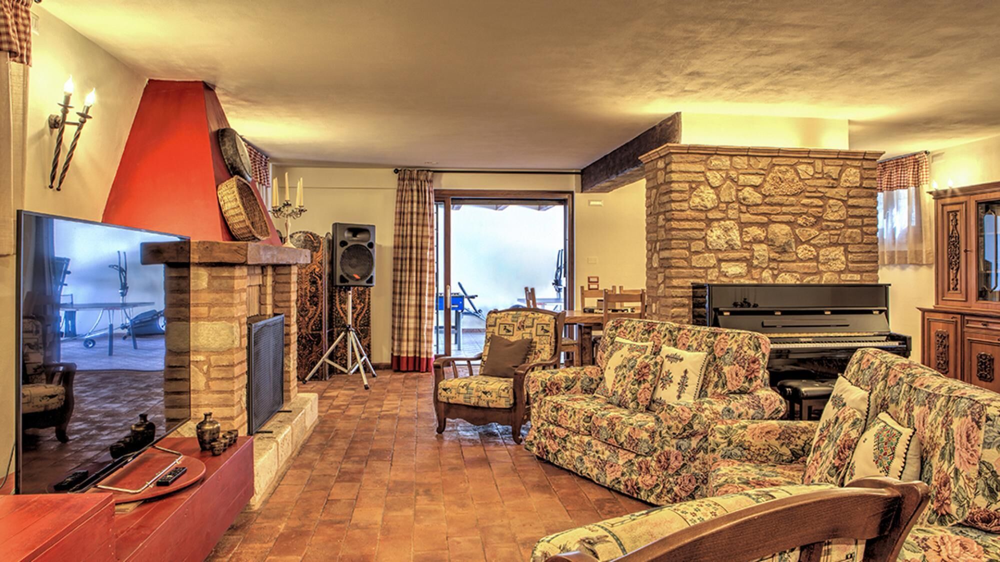 A cozy living room with a fireplace, a television, a piano, and a sofa.
