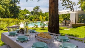 An outdoor dining area with a pool view, green table settings, and a basket of bread. - La Casa Di Nan 8 in Forli (Forlì)
