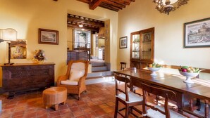 A dining area with a wooden table and chairs, a buffet table with fruit, and a staircase leading to an upper level. - Villa Primo Sole 22 (Lucca)