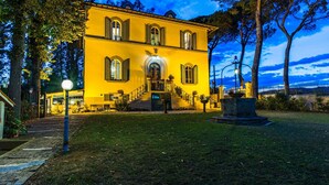 A two-story yellow building with a central entrance, a staircase, and a small garden area with a lamp post. - Villa Leonardo 30 6 (Figline e Incisa Valdarno)