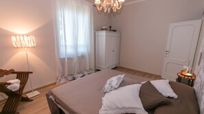 Une chambre à coucher comprenant un lit, une armoire, une chaise, une lampe et un lustre.