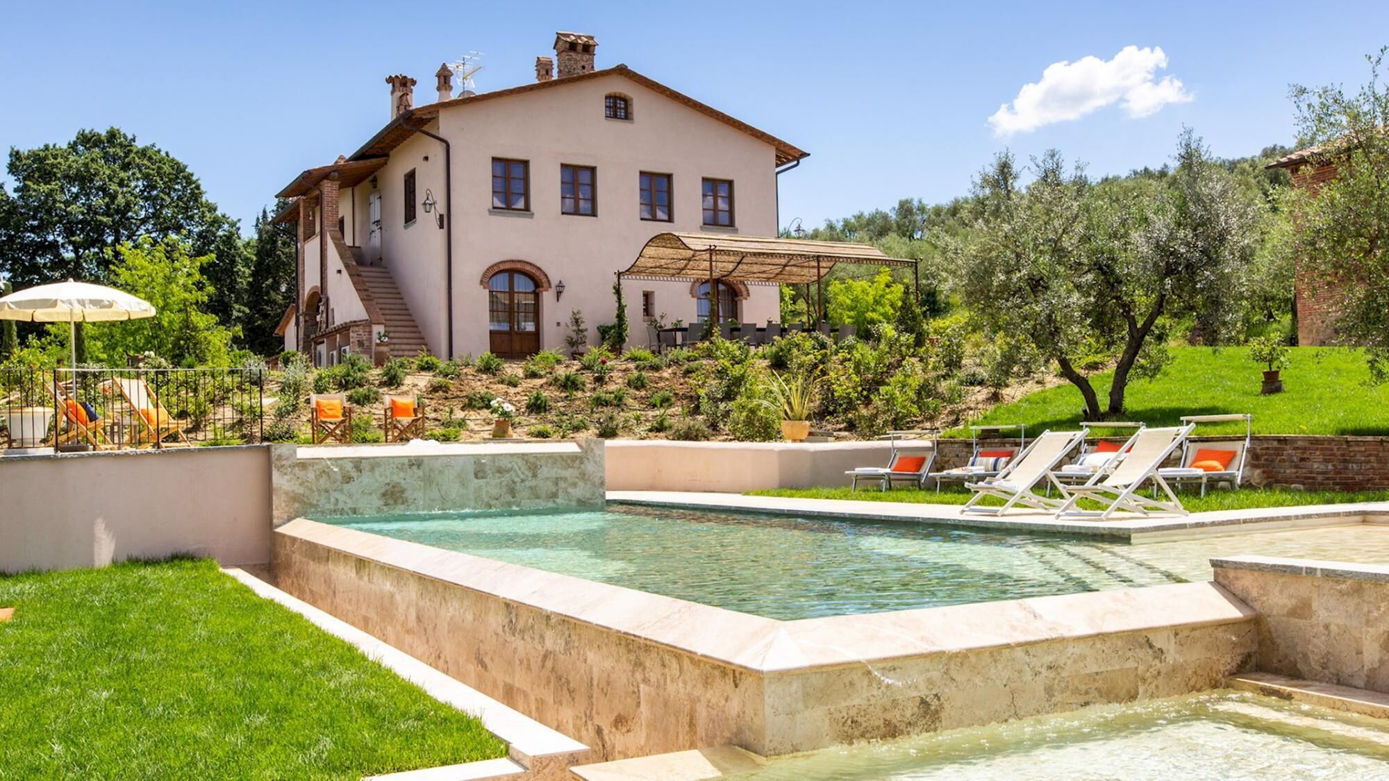 A large house with a swimming pool, outdoor seating, and a garden.