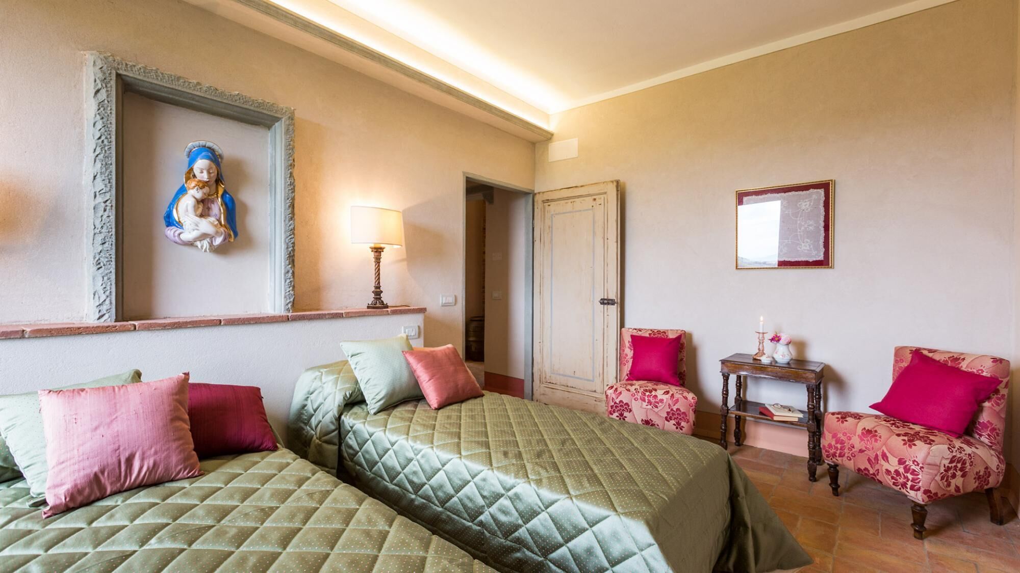 A hotel room with two beds, a chair, a small table, and a mirror.