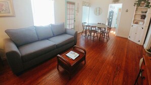 Un salon comprenant un canapé, une table basse, une table à manger, des chaises et un ventilateur de plafond.