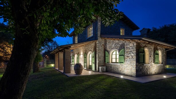 A stone house with green shutters and a large planter in the front yard. - Villa Elsa 6 in La Vigna (Villafranca in Lunigiana)
