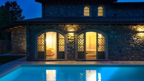 A stone building with a swimming pool in front. There are two arched windows with glass panels and a door. - Villa Elsa 6 in La Vigna (Villafranca in Lunigiana)