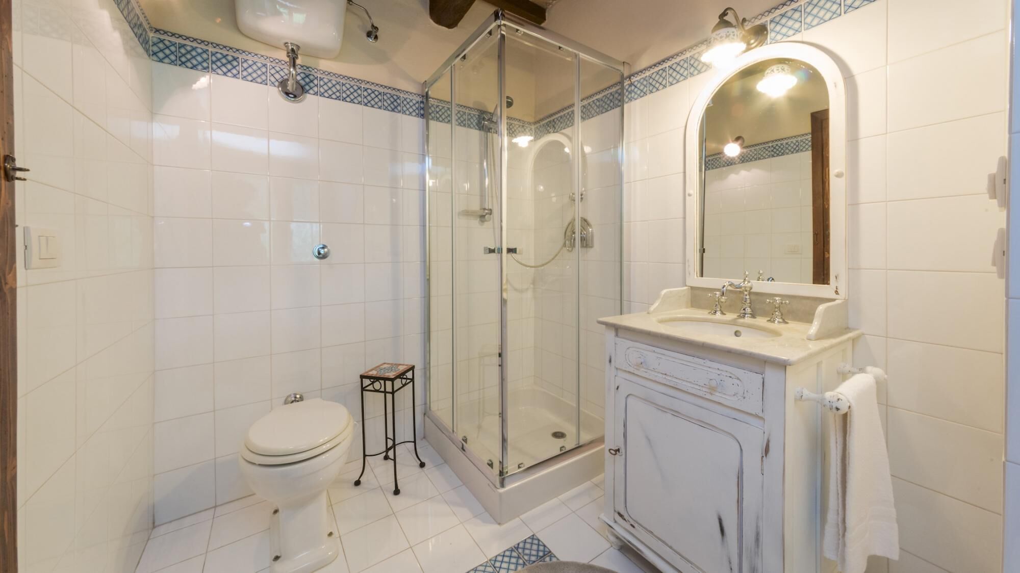 A bathroom with a glass-enclosed shower, a toilet, and a sink with a mirror.