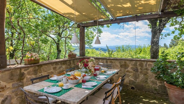 A stone table set for breakfast with a view of greenery and distant mountains. - La Cerqua 8 in Gualdo Cattaneo (Gualdo Cattaneo)