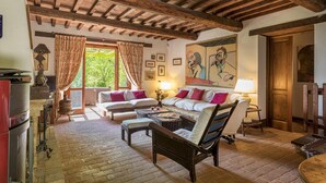 A cozy room with a wooden ceiling, a sofa set, a chair, and a table with a lamp. - La Cerqua 8 in Gualdo Cattaneo (Gualdo Cattaneo)