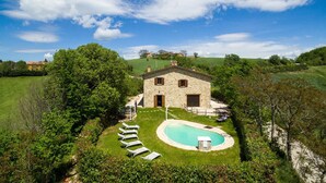A stone house with a swimming pool, surrounded by lush greenery and a clear sky. - Villa Agostini 10 in Ponte Doccia (Piandimeleto)