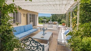 An outdoor patio with a blue sofa, a white table, and a white bench. - Quercia Felice 17 in Manciano (Manciano)