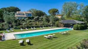 A large rectangular swimming pool with multiple lounge chairs and a covered seating area.