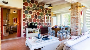 A cozy living room with a TV, dining area, and a fireplace. - Cottage Violapo 2 2 (Civitella Paganico)