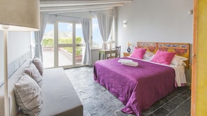 Quarto com cama, cadeira, mesa e vista para o exterior.