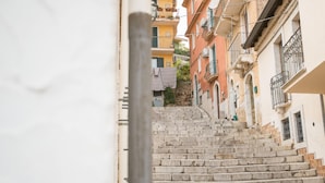 Uma rua estreita com degraus de pedra que levam a um edifício com varandas e roupa a secar do lado de fora.