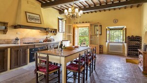 Uma cozinha com mesa e cadeiras de madeira, fogão e janela com vista para o verde.