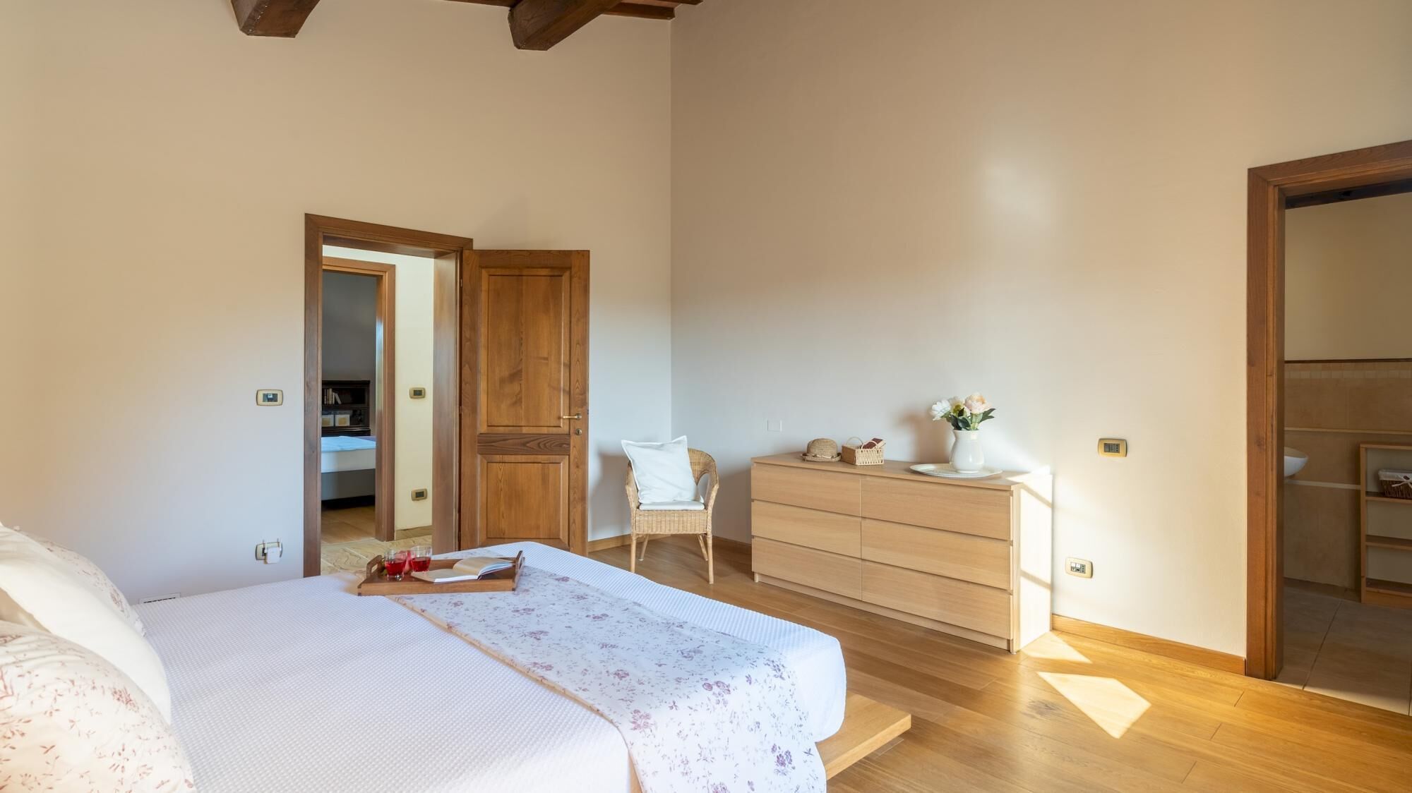 Un dormitorio con una cama, un aparador, una silla y una puerta que da a otra habitación.