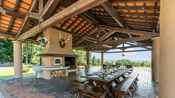 Enjoy al fresco dining in this charming outdoor space with a stone fireplace, wooden picnic tables, and a view of the surrounding landscape.